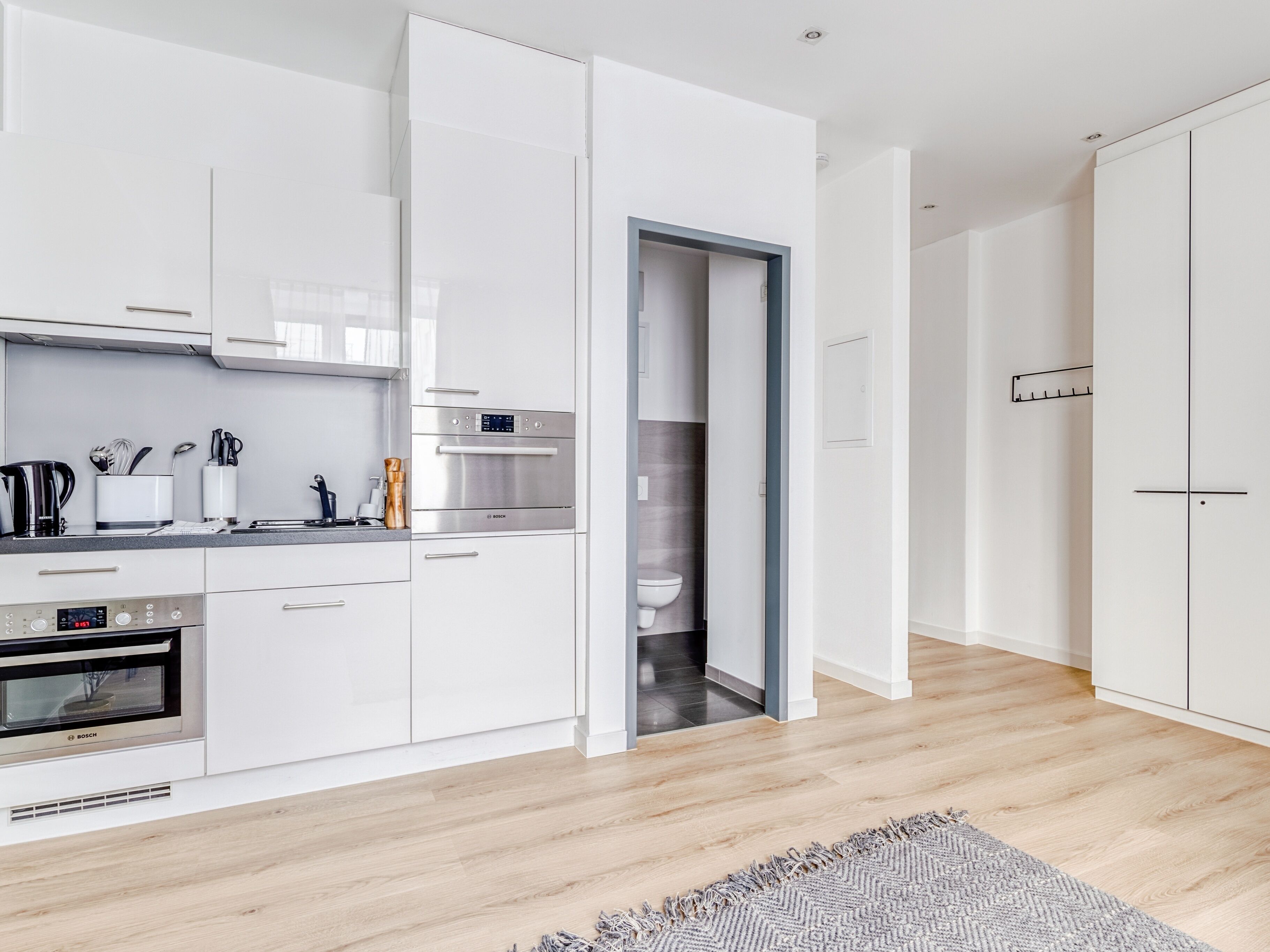 A modern kitchen with white cabinetry, a Bosch oven, and a built-in dishwasher.