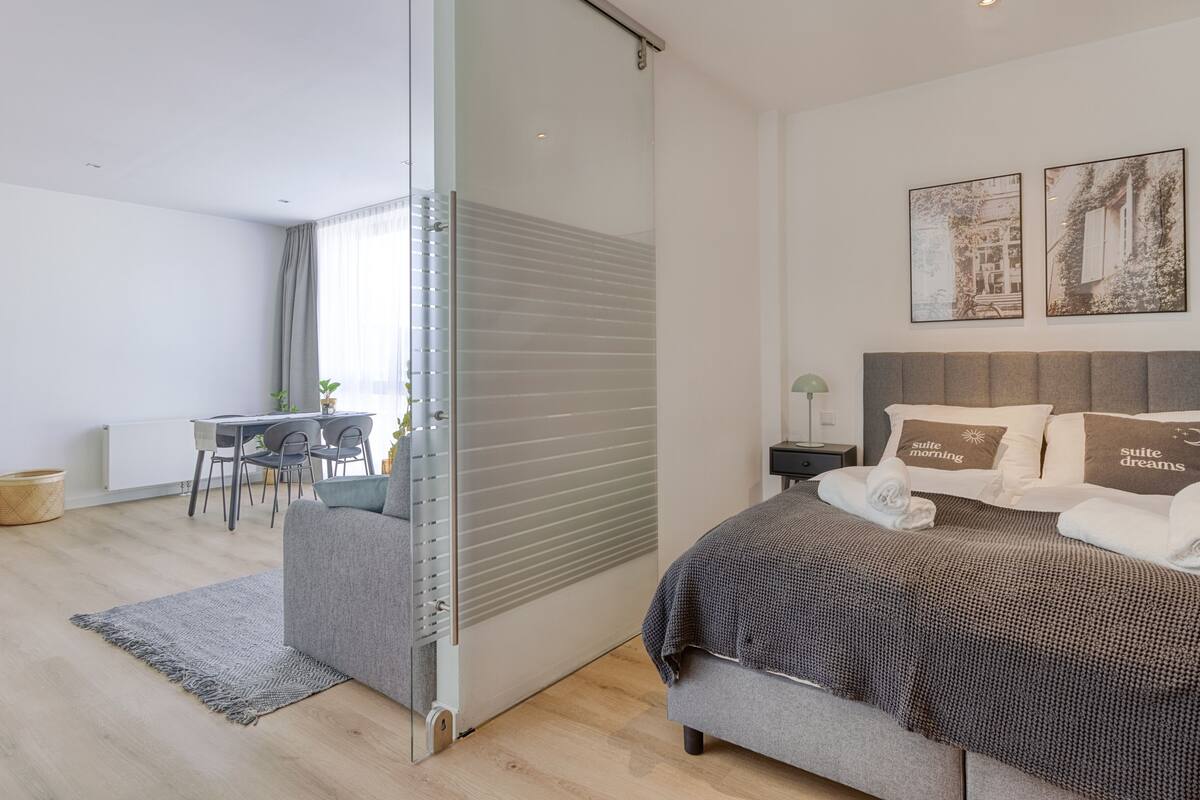 A modern bedroom with a bed, bedside tables, and a desk area.