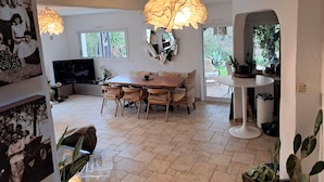 A spacious living area with a dining table, chairs, a TV, and a large window. - EXCEPTIONAL IN THE COUNTRYSIDE 15mn from BIARRITZ (Saint Pierre d'Irube)