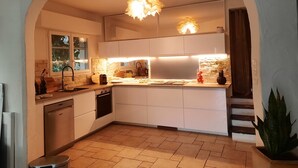 A modern kitchen with white cabinets, a built-in oven, a dishwasher, and a sink. There is a window providing natural light, and a staircase leading to another level. - EXCEPTIONAL IN THE COUNTRYSIDE 15mn from BIARRITZ (Saint Pierre d'Irube)