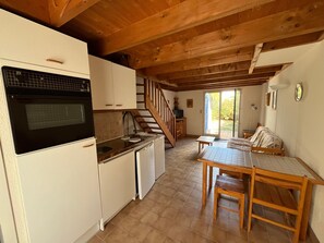 A compact kitchen with a stove, sink, and cabinets, leading to a dining area with a table and chairs.