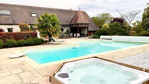 Una piscina con hidromasaje, sillas de descanso y un área exterior techada.