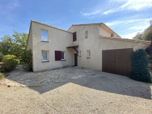 A two-story house with a gravel driveway and a wooden gate.