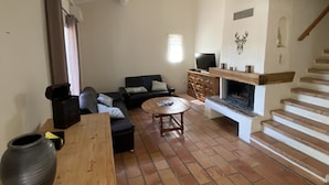 A living room with a fireplace, a sofa, a coffee table, and a TV.