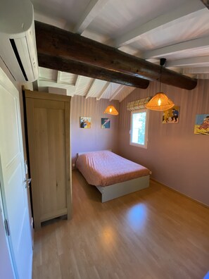 A bedroom with a wooden bed, a window, and a hanging light fixture.