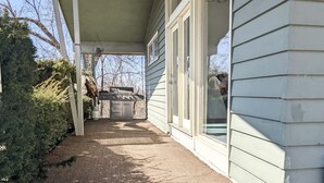 A covered porch with a barbecue grill, a concrete path, and a house with siding. - Cheerful 3 BR Residential Home in Small Town USA (woodsfield)