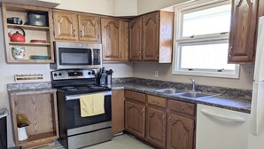A kitchen with wooden cabinets, a stainless steel stove, a microwave, and a sink. - Cheerful 3 BR Residential Home in Small Town USA (woodsfield)