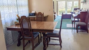 A dining area with a wooden table and chairs, a ceiling fan, and a view of the outdoors through large windows. - Cheerful 3 BR Residential Home in Small Town USA (woodsfield)