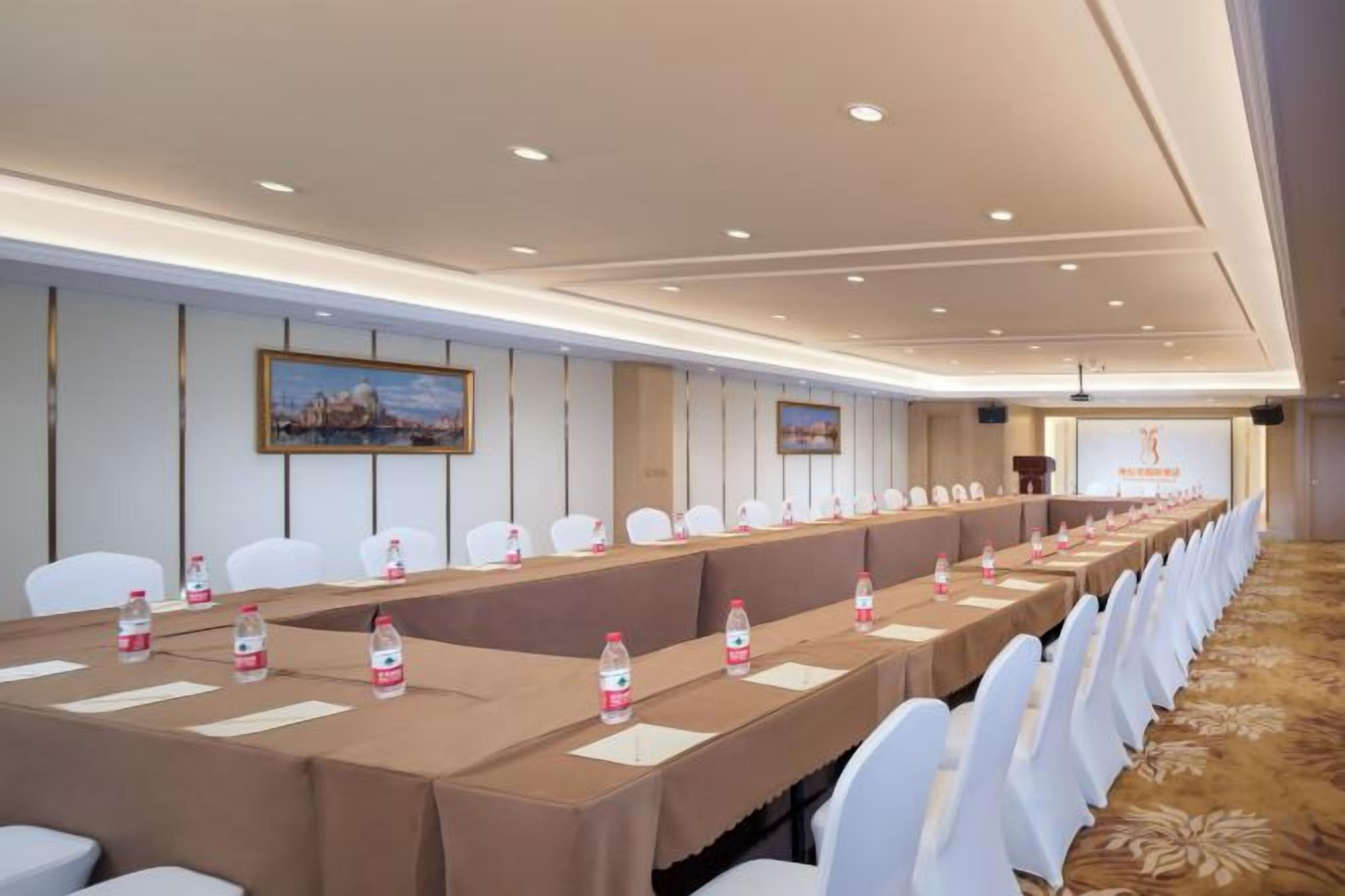 A conference room with a long table, white chairs, and water bottles.