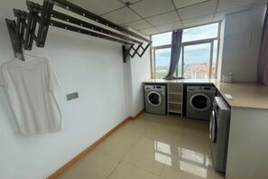 A laundry room with a drying rack, washing machines, and a view through a window. - Vienna International Hotel (Danzhou Yangpu) (Danzhou)