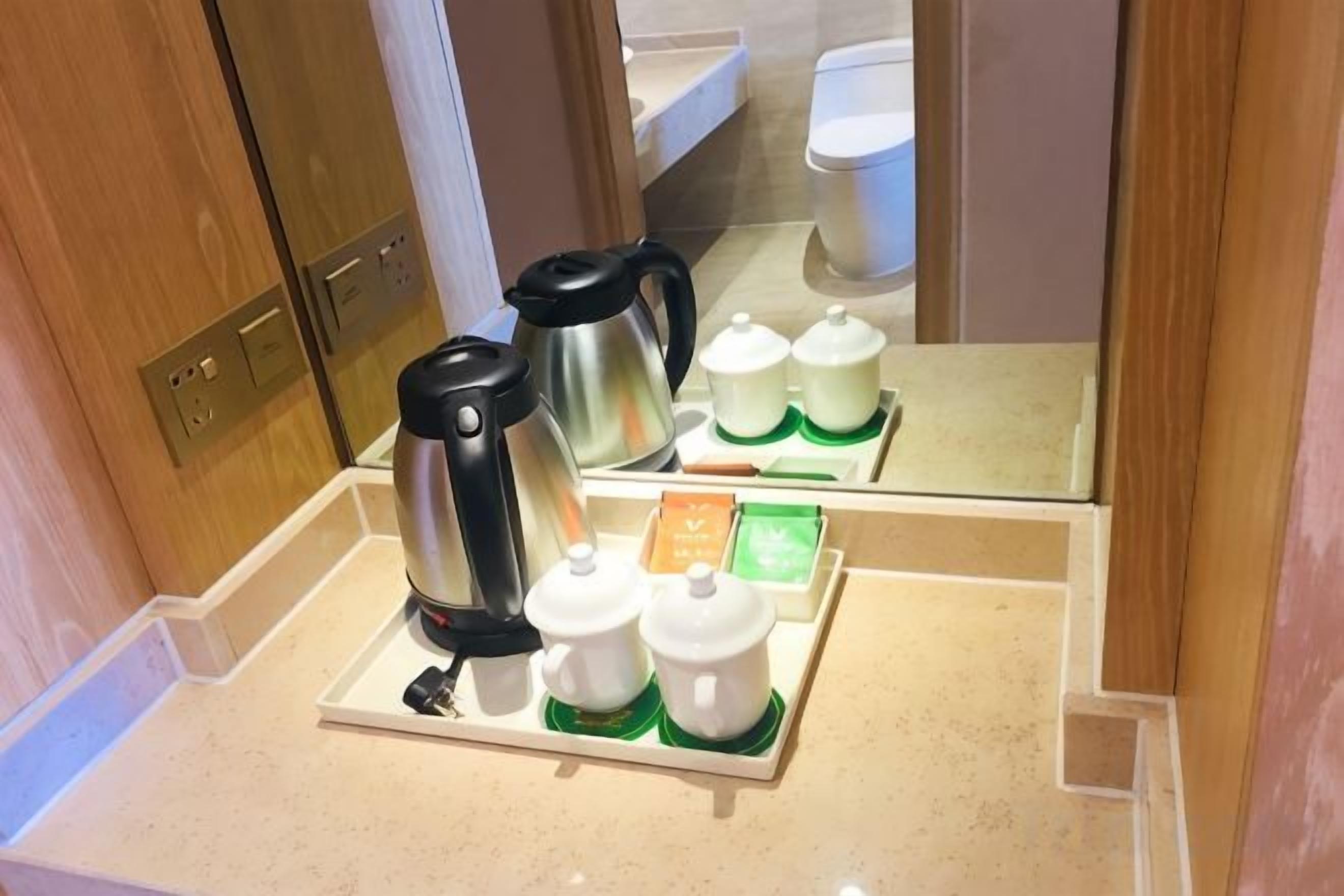 Mini-køkken med kaffemaskine, tepotte og bakke med teposer og sukker.