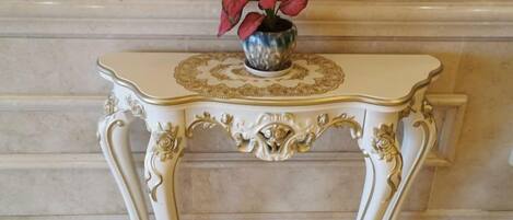 A white ornate table with a decorative top and a vase with red flowers.