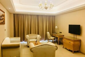 A hotel room with a sofa, armchairs, a TV, a desk, and a chandelier. - Vienna International Hotel (Danzhou Yangpu) (Danzhou)