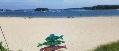 Une plage avec un panneau indiquant : « VEUILLEZ GARDER CETTE PLAGE PROPRE », et une poubelle à proximité.