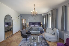 Une chambre spacieuse avec un grand lit, un lustre et une vue sur la ville.