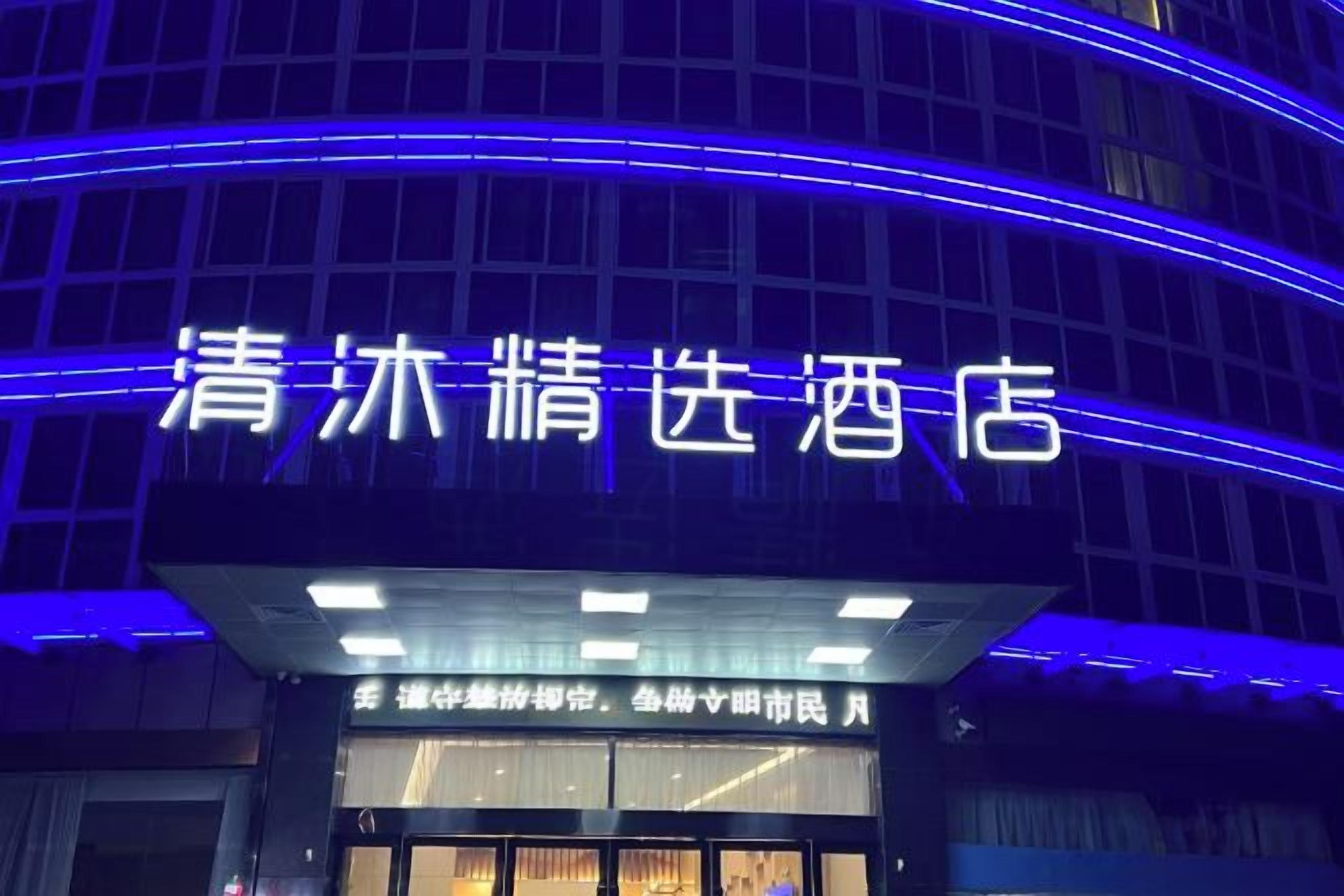 Un letrero de hotel con luces de neón azules iluminadas y caracteres chinos.