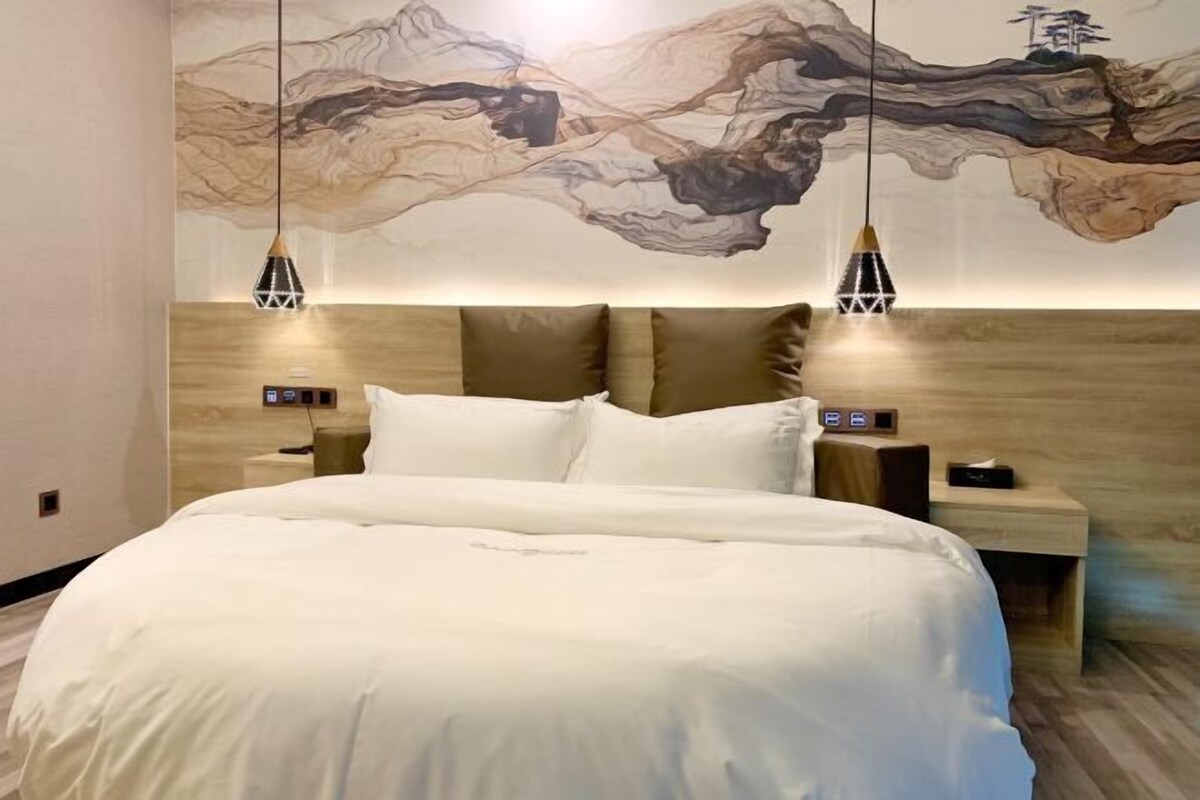 Une chambre moderne avec un grand lit, une tête de lit en bois, deux tables de chevet et une fresque murale.