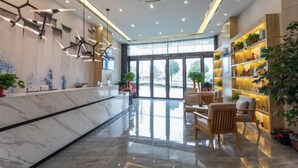 A modern hotel lobby with a marble reception desk, wooden seating, and a large window offering a view of the outdoors. - Qingmu Select Hotel (Jintan No.4 Middle School Yaoban Branch) (Changzhou)