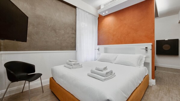 Una habitación de hotel moderna con una cama grande, una silla negra y un cuadro en la pared.