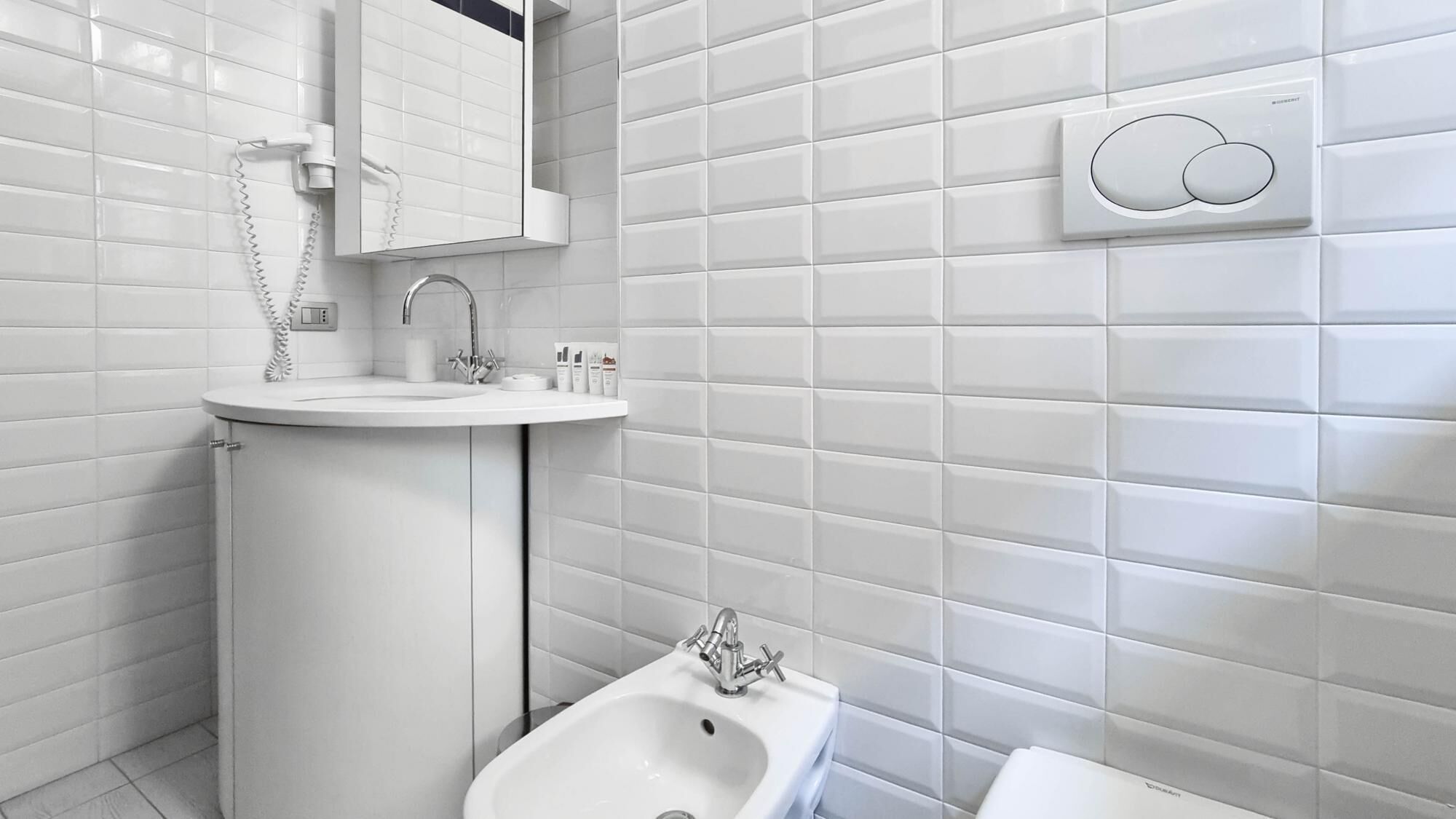 A modern bathroom with a white sink, vanity, and bathtub.