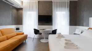 A modern hotel room with a large bed, a sofa, a small round table, and two chairs. - Italianway Collection - Corso Venezia 7 - Aida (Milan)