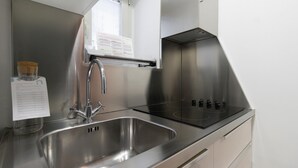 Una cocina de acero inoxidable con pileta, grifo y estufa.