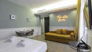 Habitación de hotel con cama, sofá, escritorio y un letrero de neón.