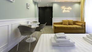 Habitación de hotel con cama, una mesita con sillas, un sofá y un letrero de neón en la pared.