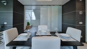A modern dining area with a black table set for four, white chairs, and a glass partition in the background. - Italianway Collection - Corso Venezia 7 - Traviata (Milan)