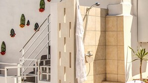 Een badkamer met een douche, een handdoek aan de muur en een trap naar een andere kamer.