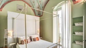 Een kamer met een hemelbed, een kleine tafel en een plank met manden.