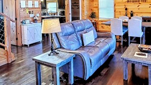 A cozy cabin interior with a leather sofa, dining table, and a kitchen area. - Panoramic Views, LED Hot Tub, King Suite, Wi-Fi, Minutes to Downtown Gatlinburg (Gatlinburg)