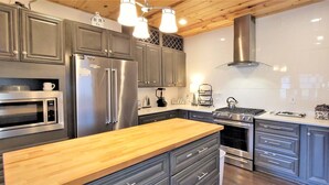 A modern kitchen with stainless steel appliances, wooden countertops, and a central island. - Panoramic Views, LED Hot Tub, King Suite, Wi-Fi, Minutes to Downtown Gatlinburg (Gatlinburg)