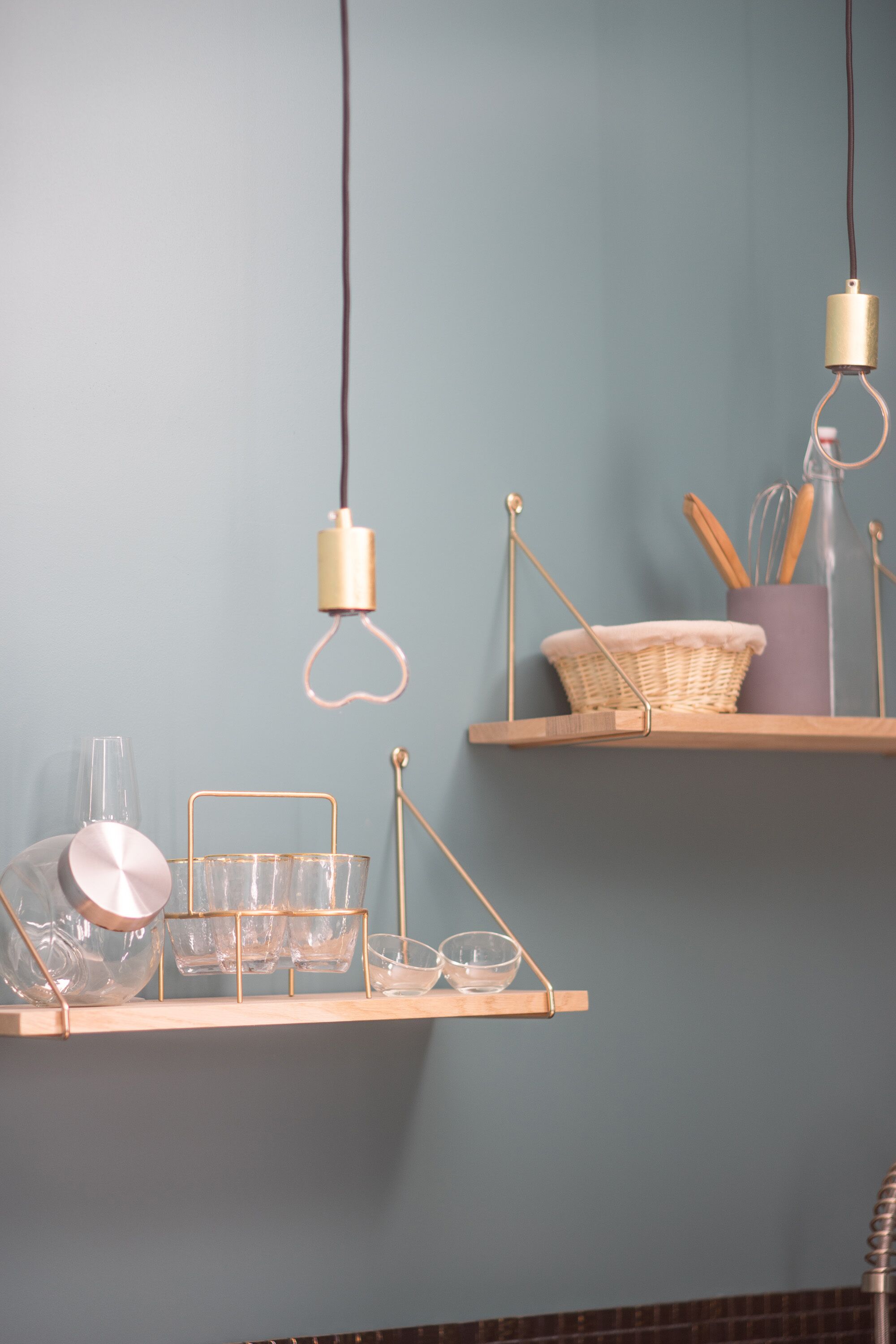 A kitchen with wooden shelves holding kitchenware and utensils.
