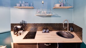 Cocina moderna con encimera de madera, un lavamanos y un salpicadero negro. Hay estantes sobre la encimera con diversos utensilios de cocina.