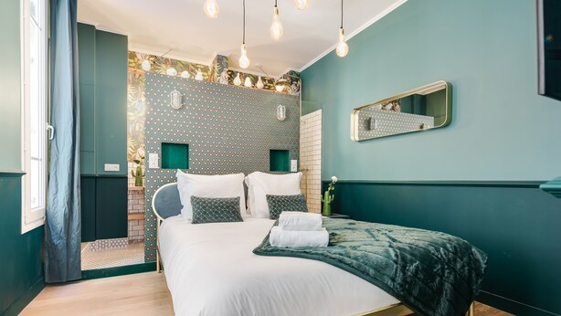 Un dormitorio con una cama, un espejo y un papel tapiz estampado.