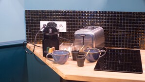 Una encimera de cocina con un tostador, una tetera y varias tazas y recipientes.