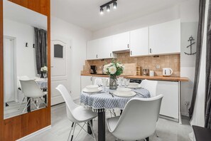A modern kitchen with white cabinets, a wooden countertop, and a dining table set for four.