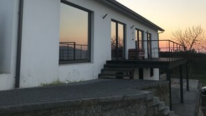 Ein modernes Gebäude mit großen Fenstern, einem Balkon und einer Steinwand davor.