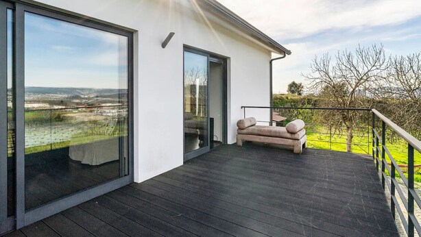 Ein modernes Haus mit Balkon, einer Couch und Blick ins Grüne.