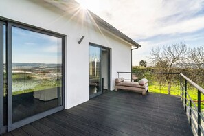 Una casa moderna con balcón, sofá y vistas al campo.