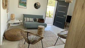 Uma sala de estar moderna com um sofá, duas poltronas, uma mesinha e uma televisão.
