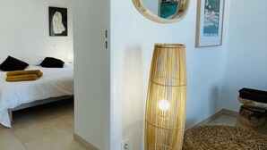 Quarto com cama, mesa de cabeceira, luminária e um quadro na parede.