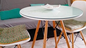 Ett modernt vardagsrum med en grå soffa, ett glasbord och turkosa kuddar. På väggen finns turkosa hyllor med växter och dekorativa föremål.