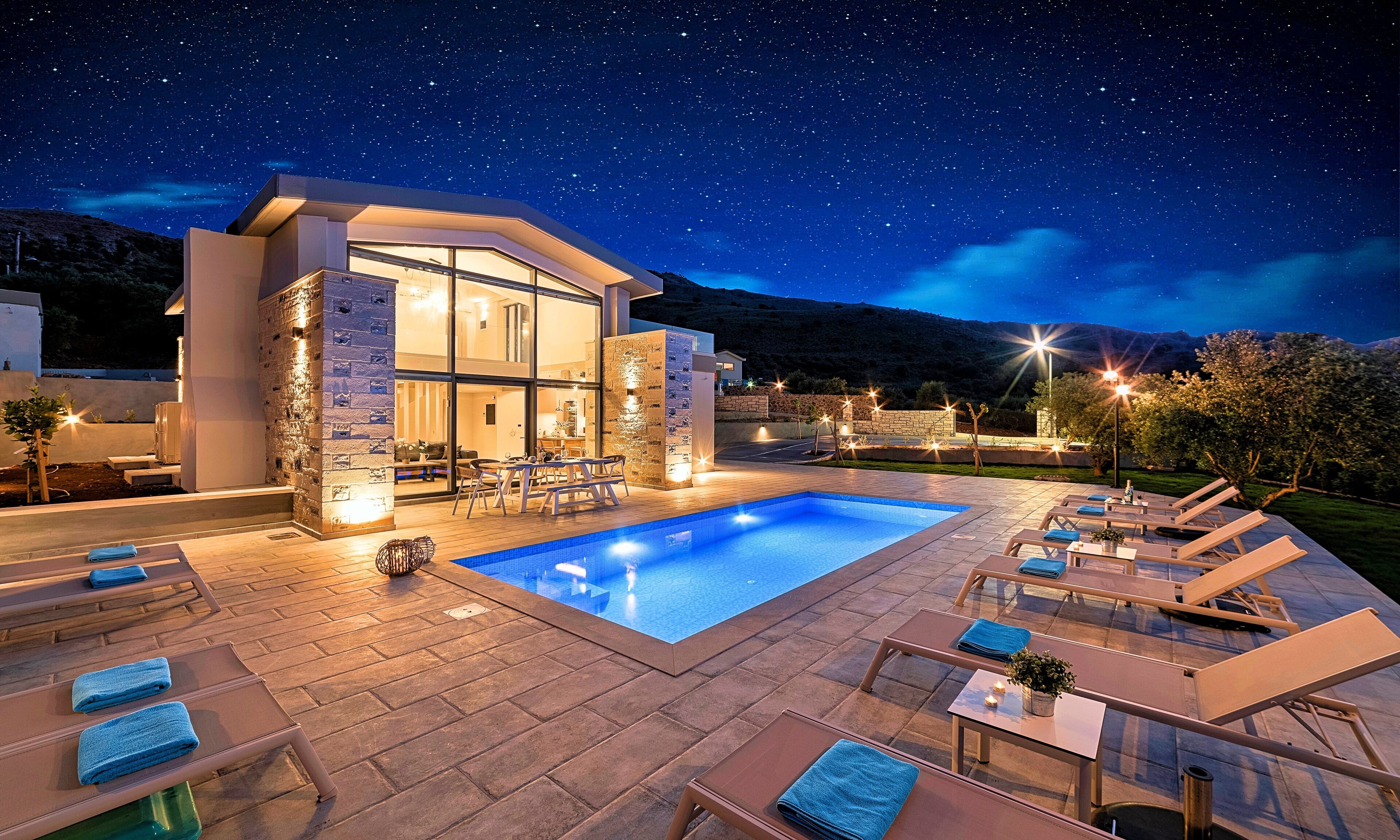 A modern poolside area with lounge chairs, a swimming pool, and a building with large windows.
