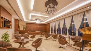 A modern hotel lobby with leather chairs, a reception desk, and large windows with curtains. - BW Suites & Spa (Manama)