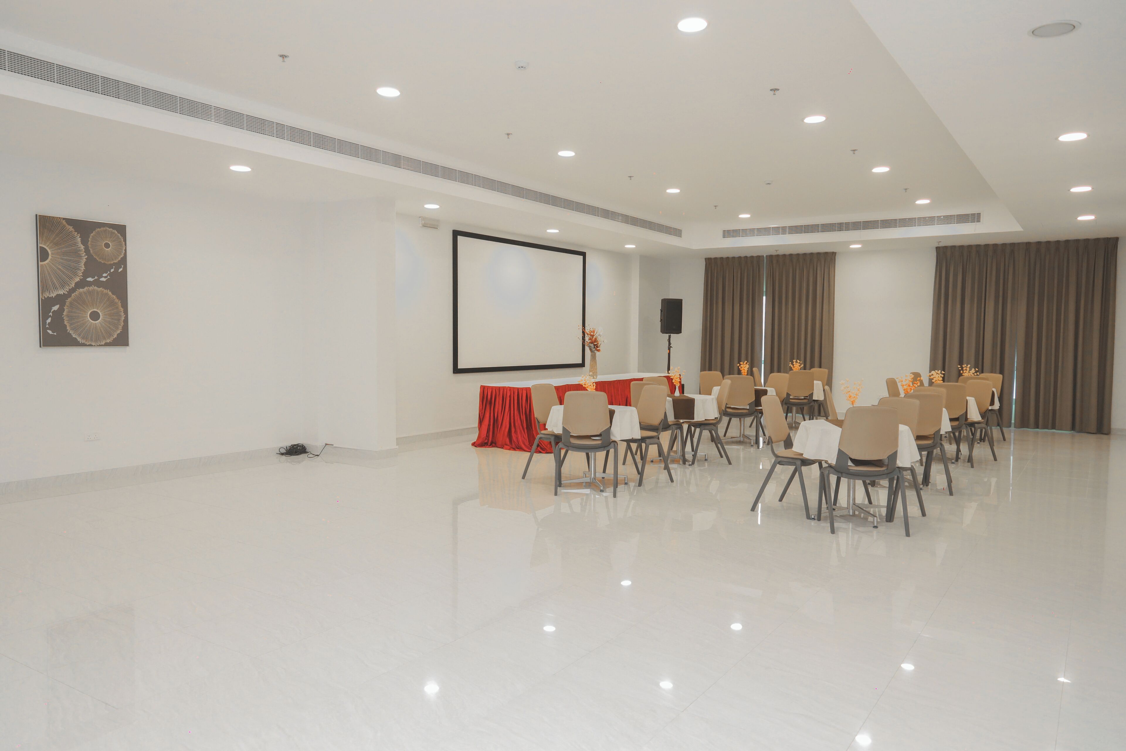 A conference room with a large screen, rows of chairs, and a speaker.
