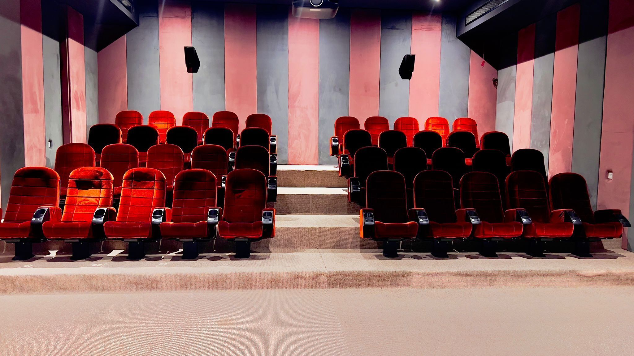 A cinema with rows of red seats and a central aisle.