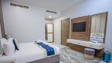 A modern bedroom with a bed, a TV mounted on a wooden panel, a bedside table, and a mirror.
