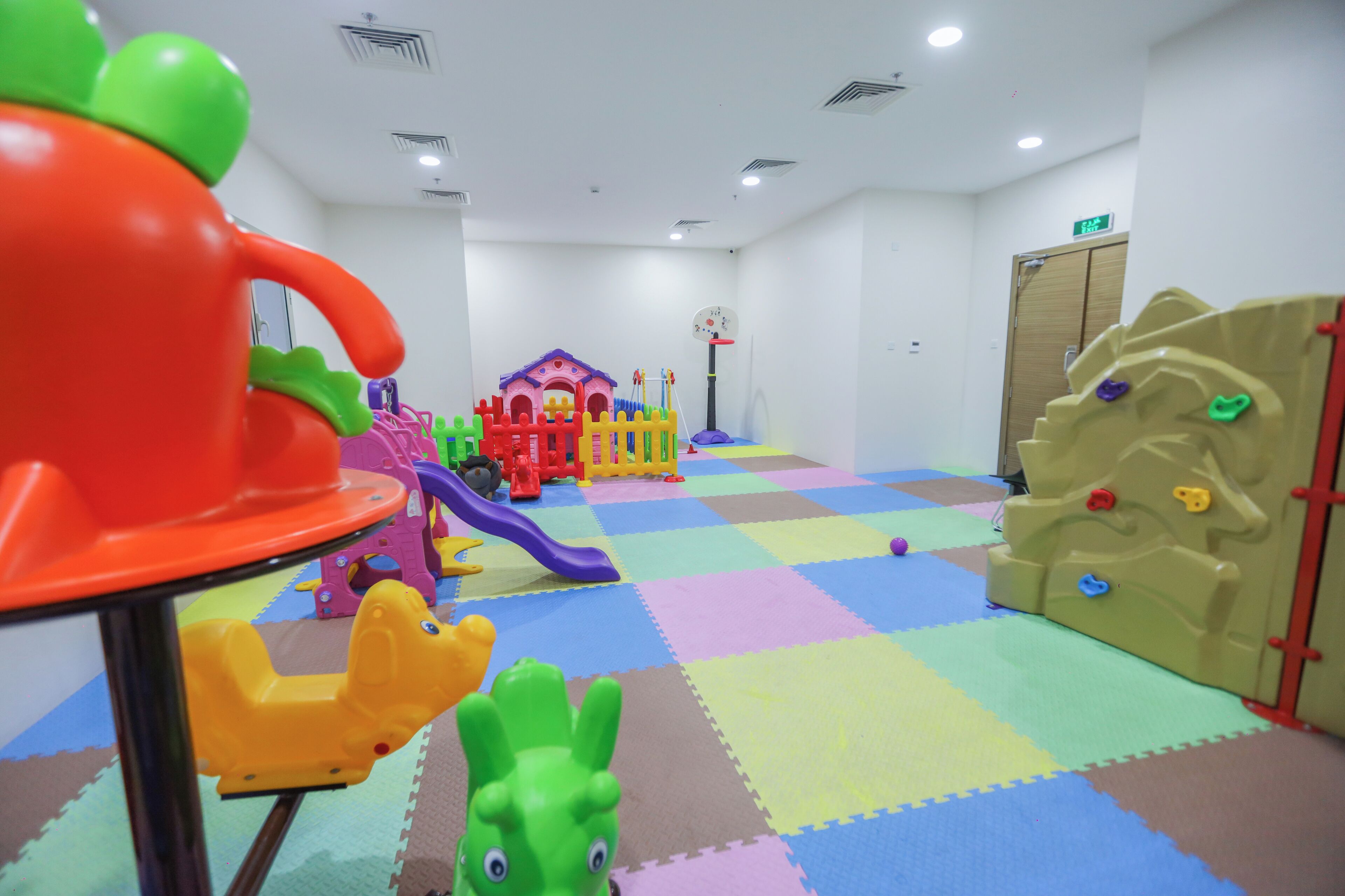 A children's play area with colorful play structures and a checkered floor.
